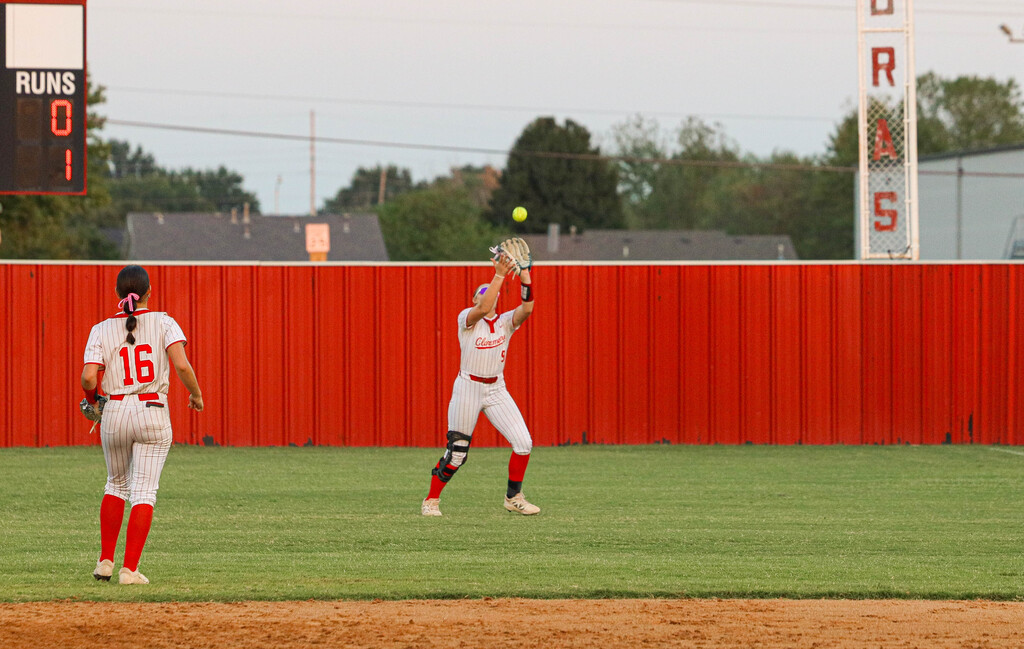 Claremore softball player reaches up to catch a fly ball in the outfield.