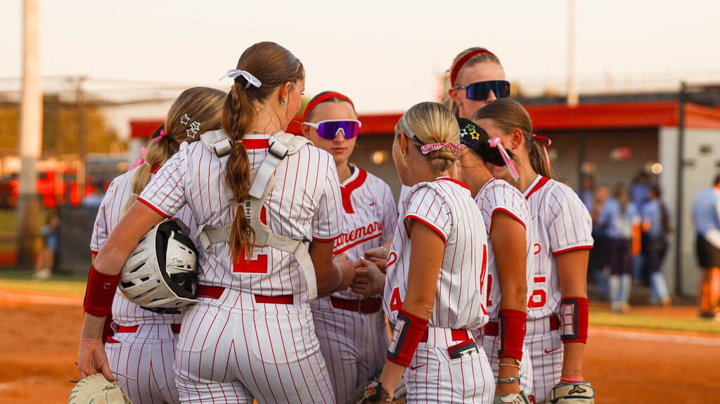 Claremore softball players gather in a team huddle on the field.