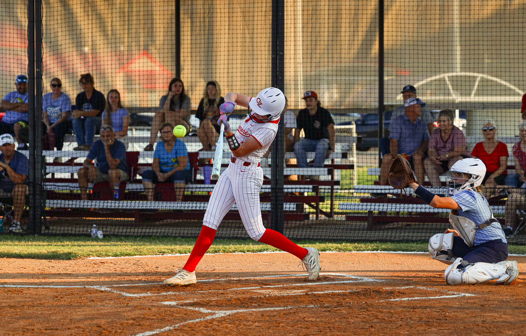 Lady Zebra batter swings at a pitch with the opposing catcher behind home plate.