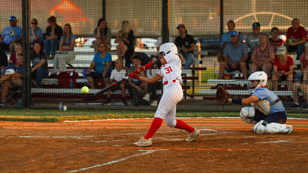 Lady Zebra batter makes contact with a softball as the catcher reaches for the pitch.