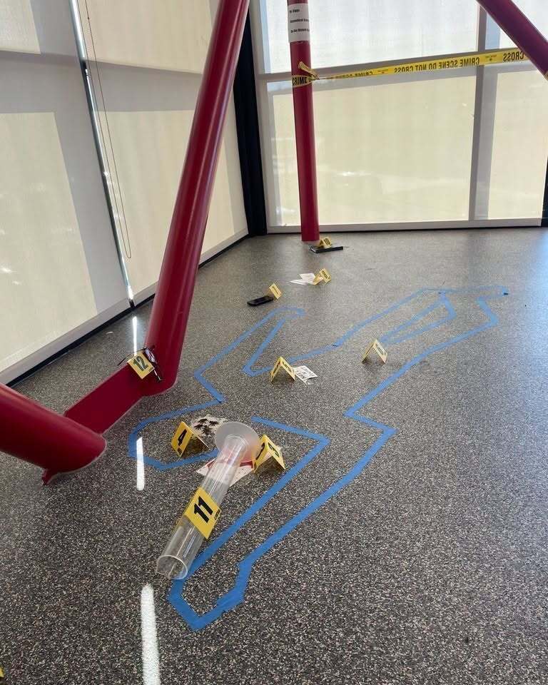 Mock crime scene with a taped body outline and numbered evidence markers.