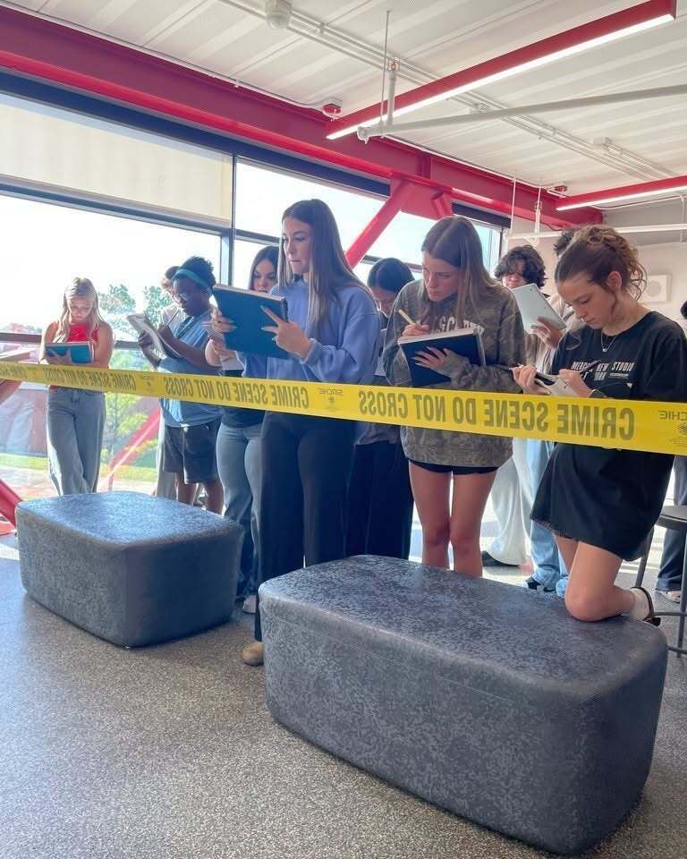 Forensic science students taking notes while examining a mock crime scene.