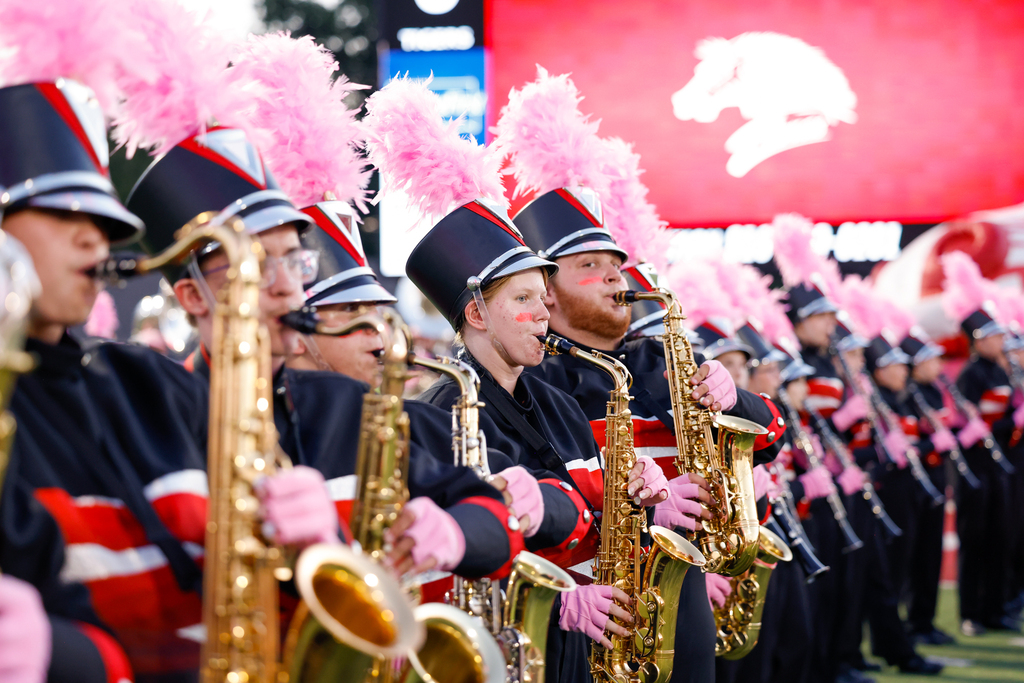 Zebra Band saxophone players perform wearing pink gloves and pink feathered plumes.