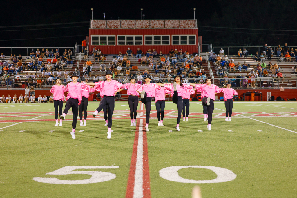 Claremore dance team members kick in unison during their Pink Out Night performance.