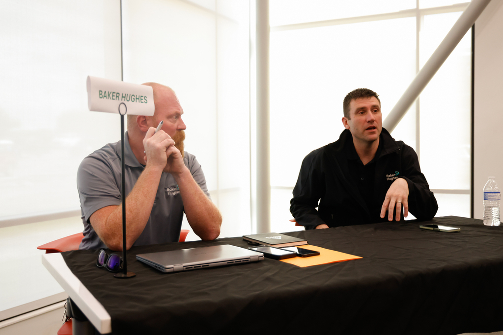Two Baker Hughes representatives sit behind a table.