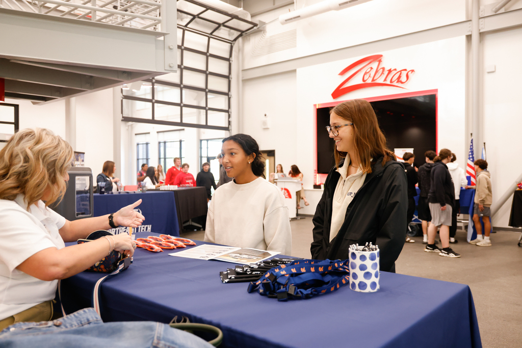Two students speak with a Reading Truck representative at a booth.