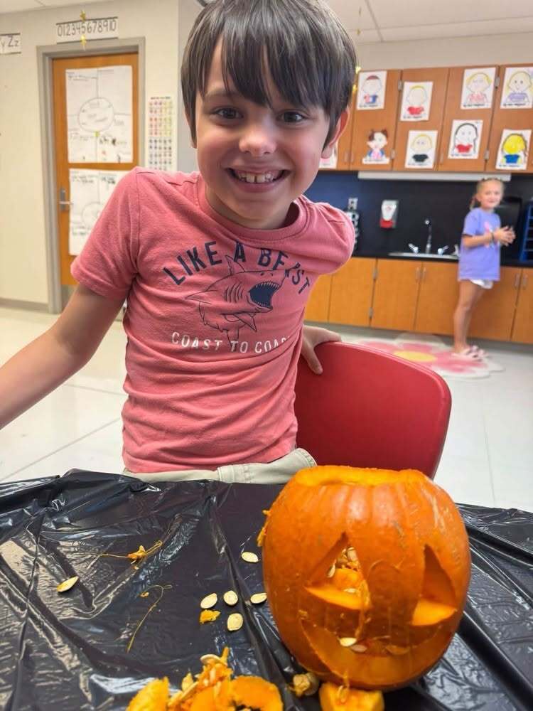A student grins while posing next to the class jack-o'-lantern.