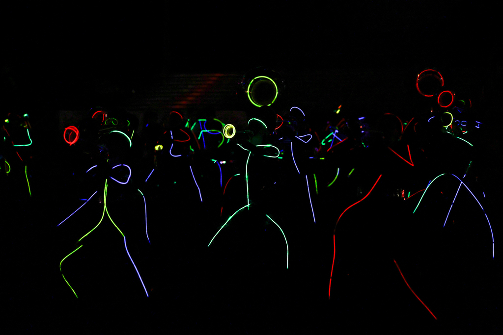 Zebra Band members perform in the dark, outlined in colorful glow sticks with illuminated instruments.