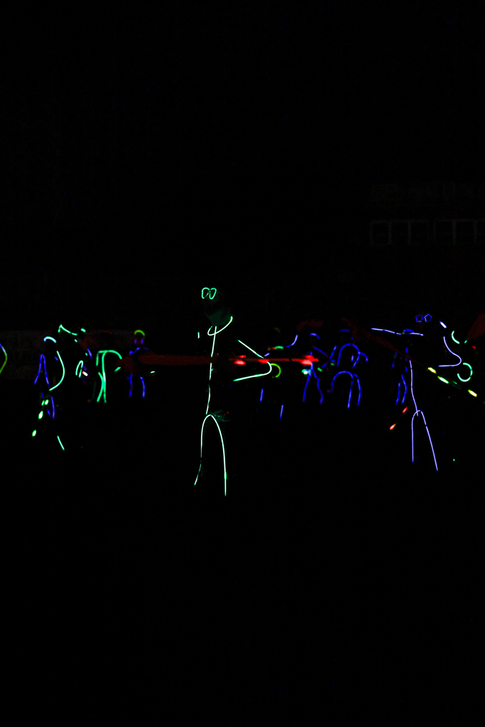 Zebra Band members perform in the dark, outlined in colorful glow sticks with illuminated instruments.