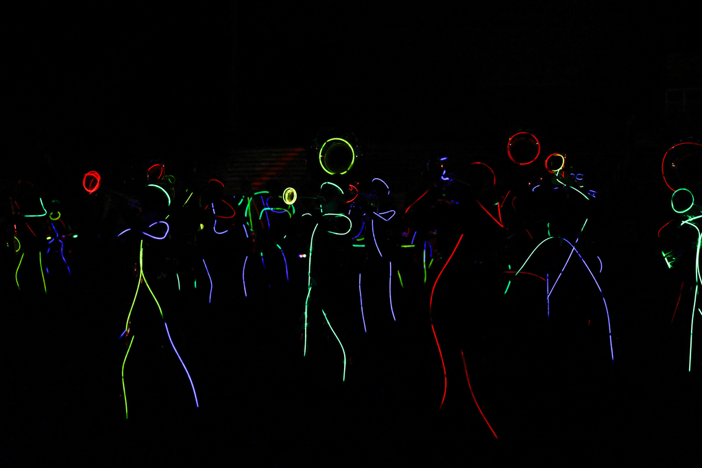Zebra Band members perform in the dark, outlined in colorful glow sticks with illuminated instruments.