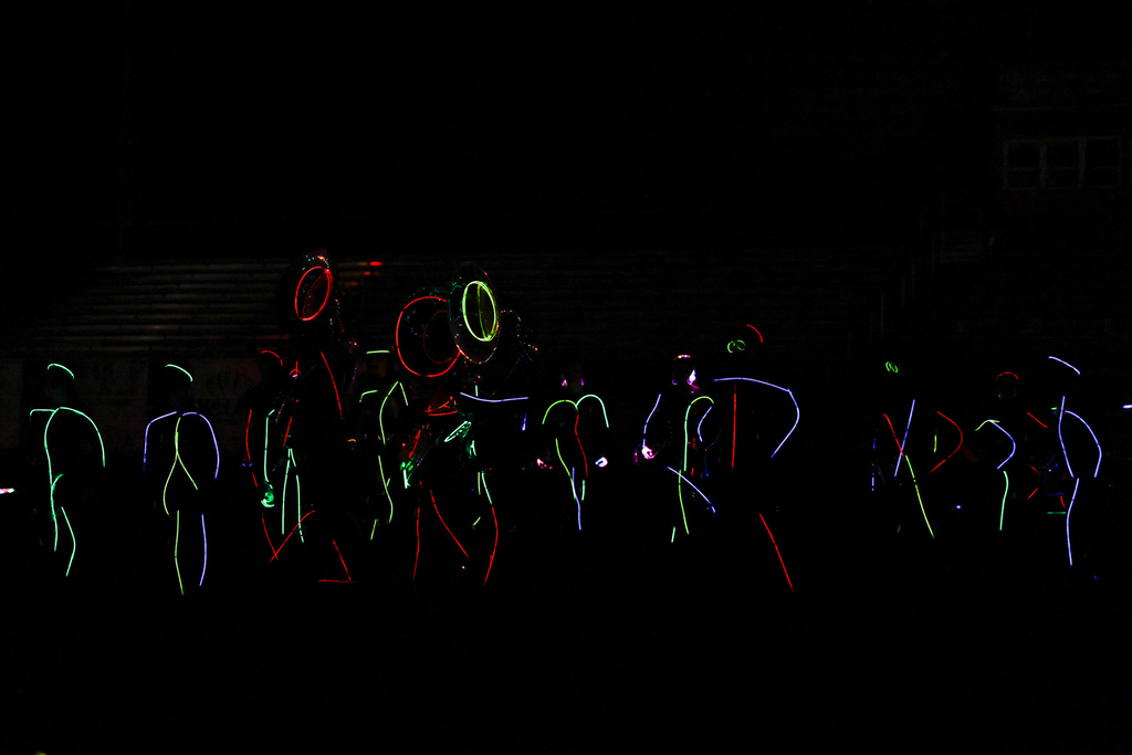 Zebra Band members perform in the dark, outlined in colorful glow sticks with illuminated instruments.