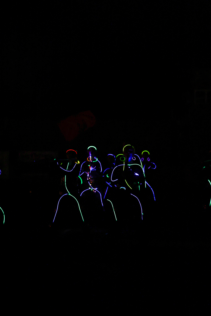 Zebra Band members perform in the dark, outlined in colorful glow sticks with illuminated instruments.