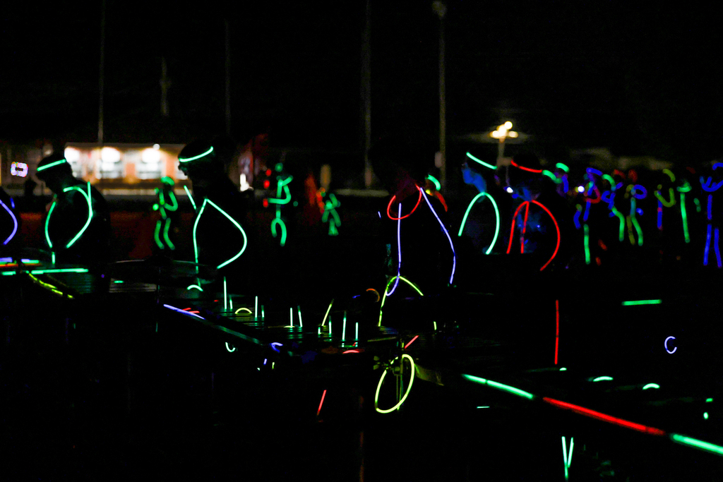 Zebra Band members perform in the dark, outlined in colorful glow sticks with illuminated instruments.