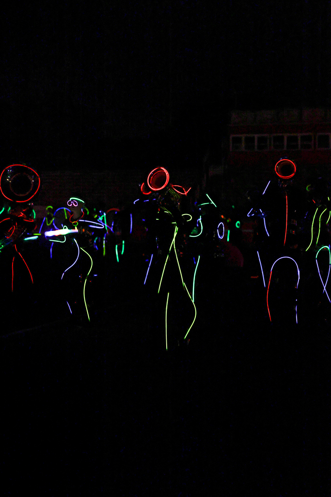 Zebra Band members perform in the dark, outlined in colorful glow sticks with illuminated instruments.