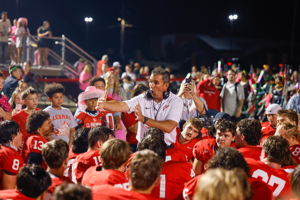 A Claremore football coach speaks to the team during a postgame huddle.