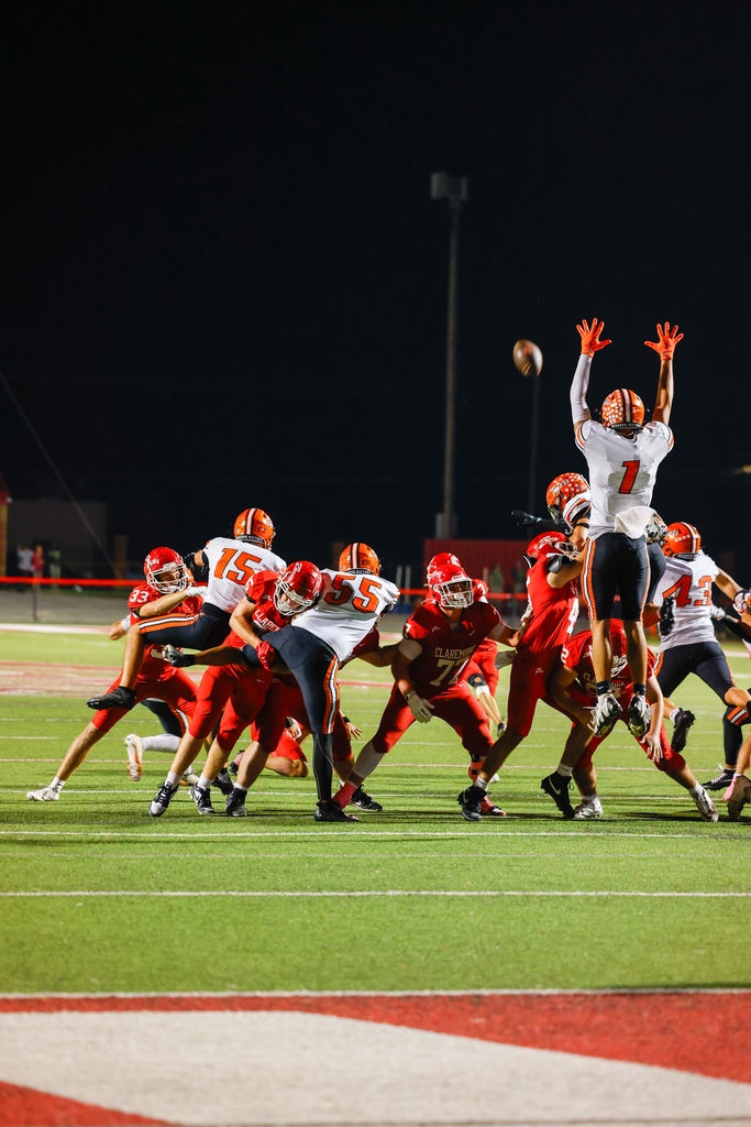 An opposing player jumps to catch a football as Claremore defenders rush toward him.