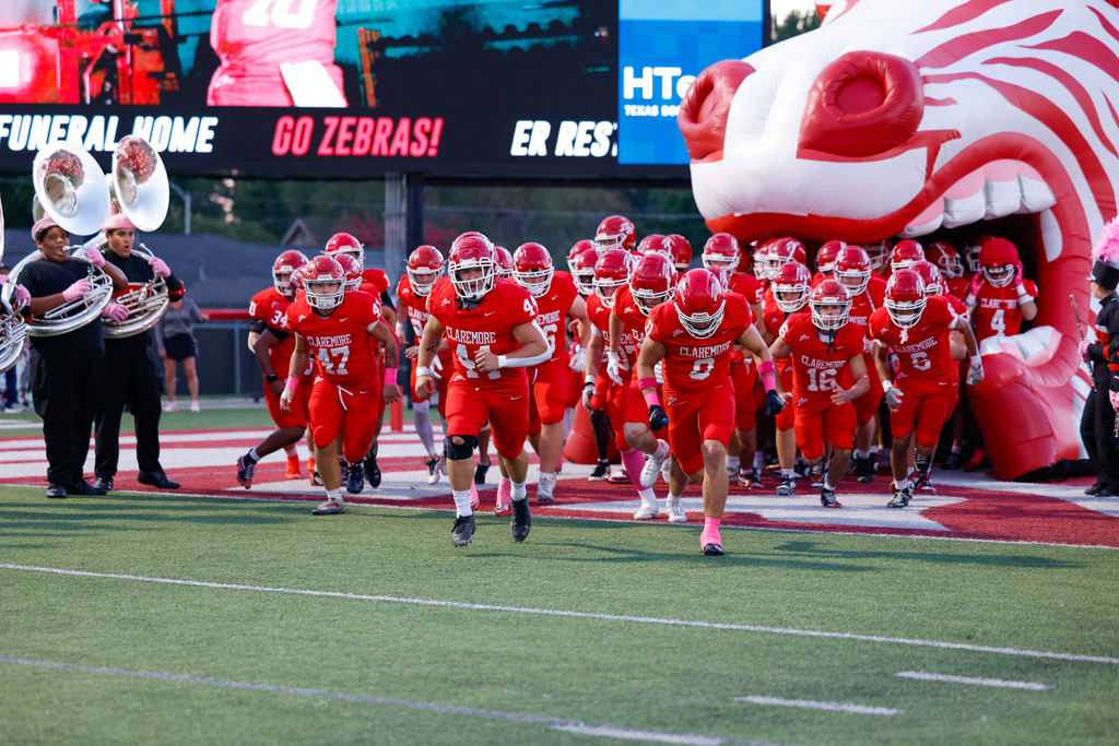 Claremore football players run onto the field through the inflatable Zebra tunnel before the game.