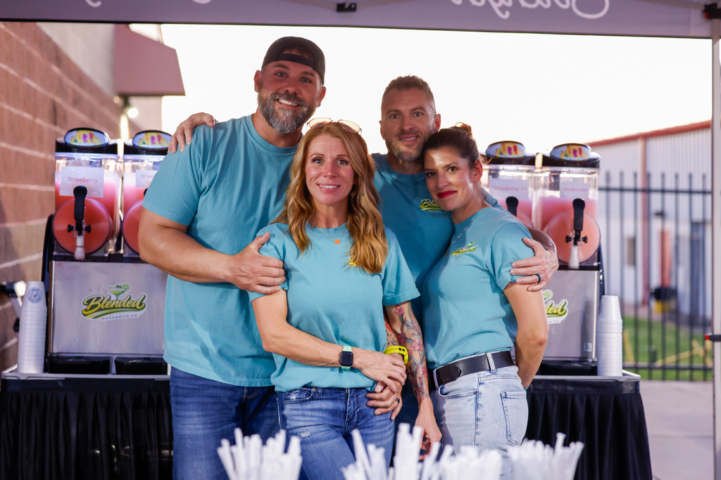 Four Blended Margarita Co. team members pose together in front of colorful slushie machines at Lantow Field.