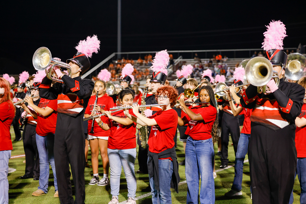 Zebra Band members in uniform perform alongside younger musicians playing flutes and other instruments.