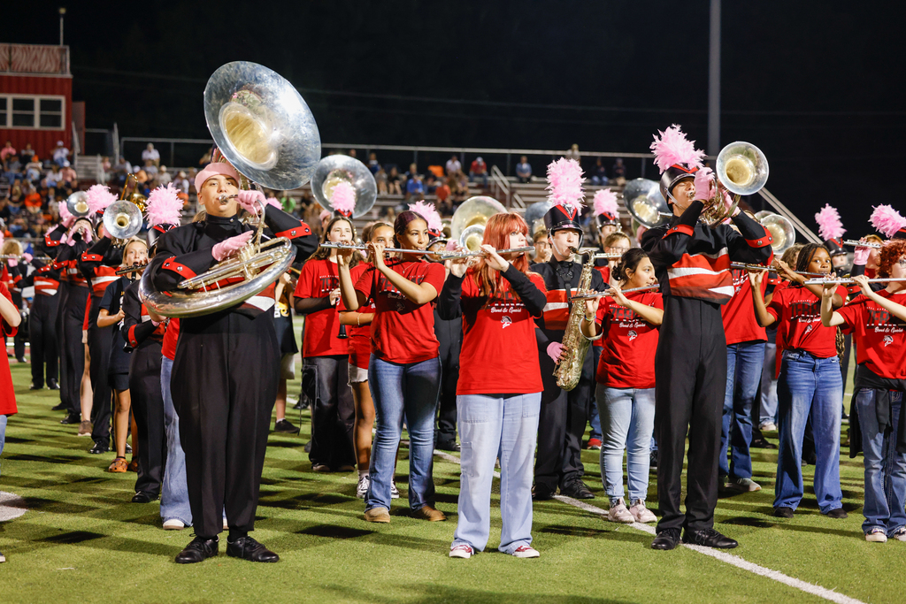 Zebra Band members and younger musicians perform together on the football field during halftime.