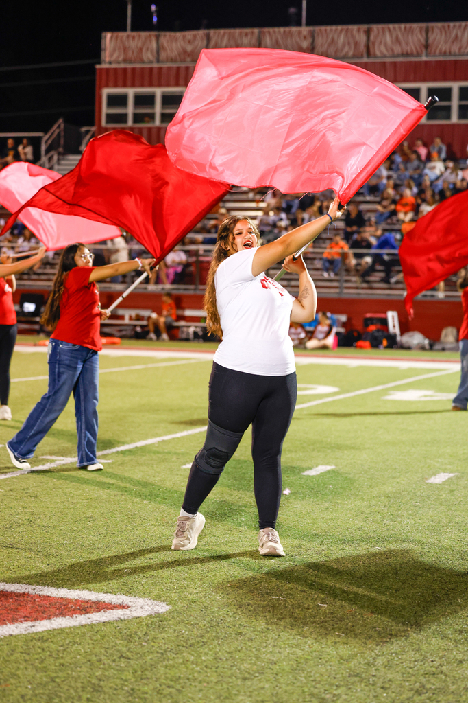Color guard members wave large red flags during the halftime performance.