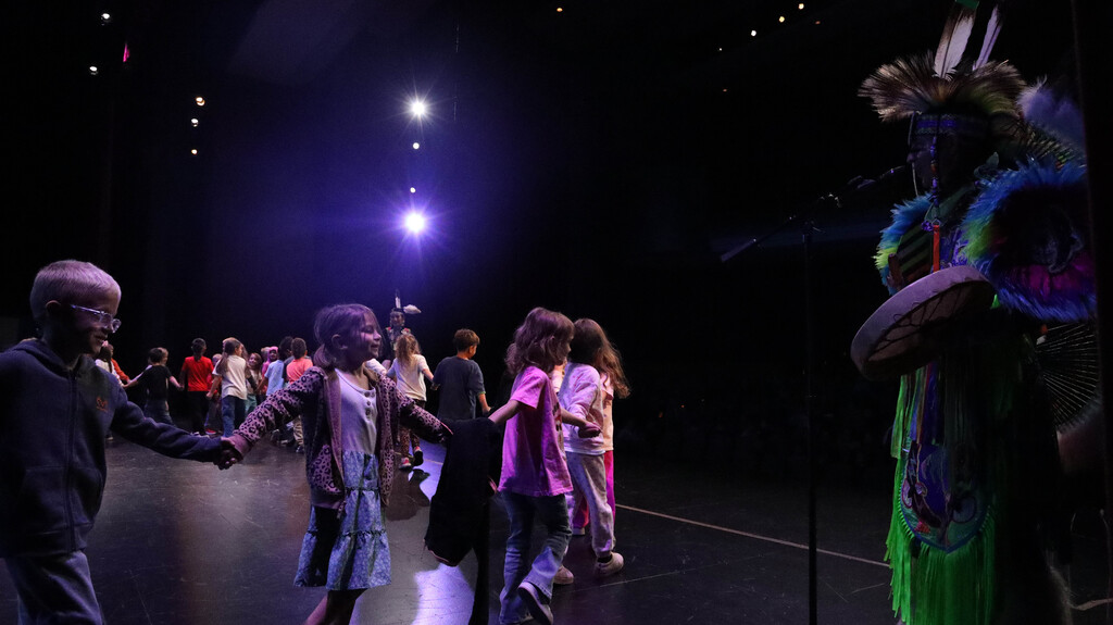 Students holding hands and dancing on stage during the Rising Buffalo performance.