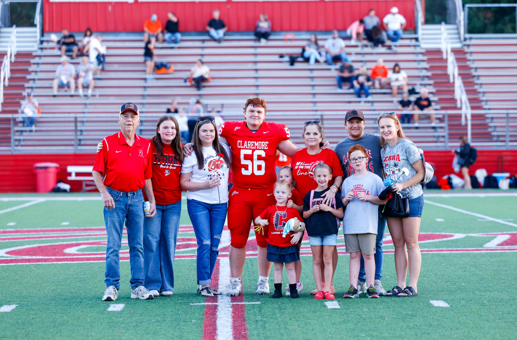 Claremore football player #56 stands with a large group of family members during Senior Night.