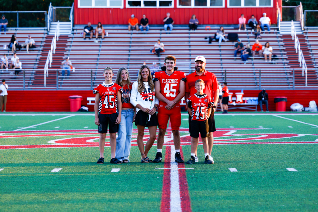 Claremore football player #45 poses with five family members on the field.