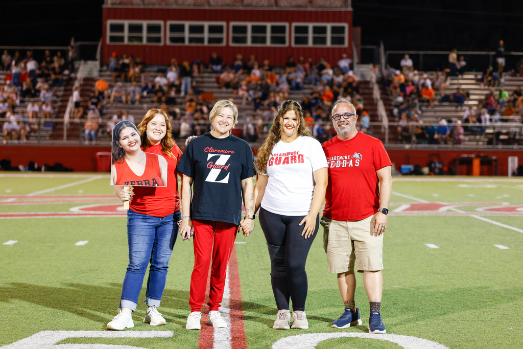 Senior color guard member poses with four family members on the football field.