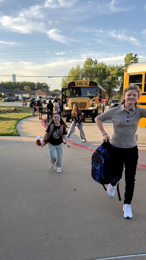 Students walk away from their school buses with backpacks as they arrive at school.