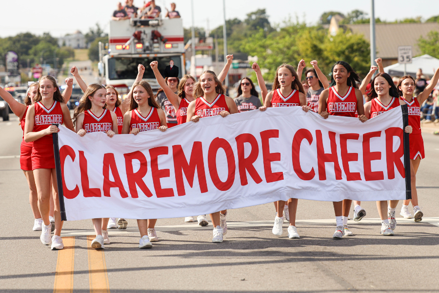 Claremore cheerleaders carry a banner during a parade.