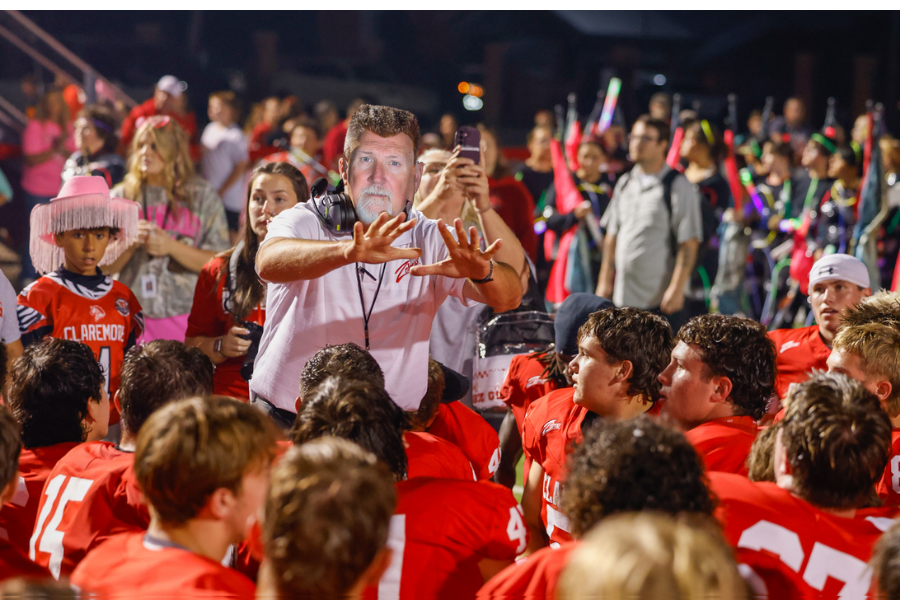 Claremore football players gather around a coach.