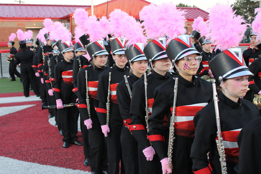 Claremore band members stand in formation with pink plumes.