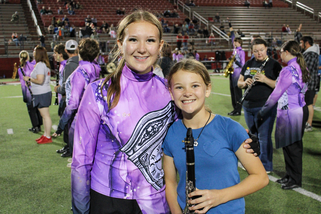 A band student poses with a younger participant holding a clarinet.