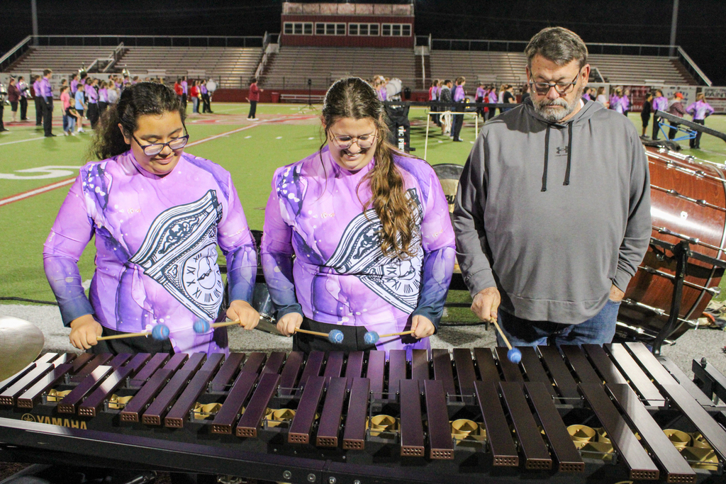 Two band students and a parent practice playing the marimba.