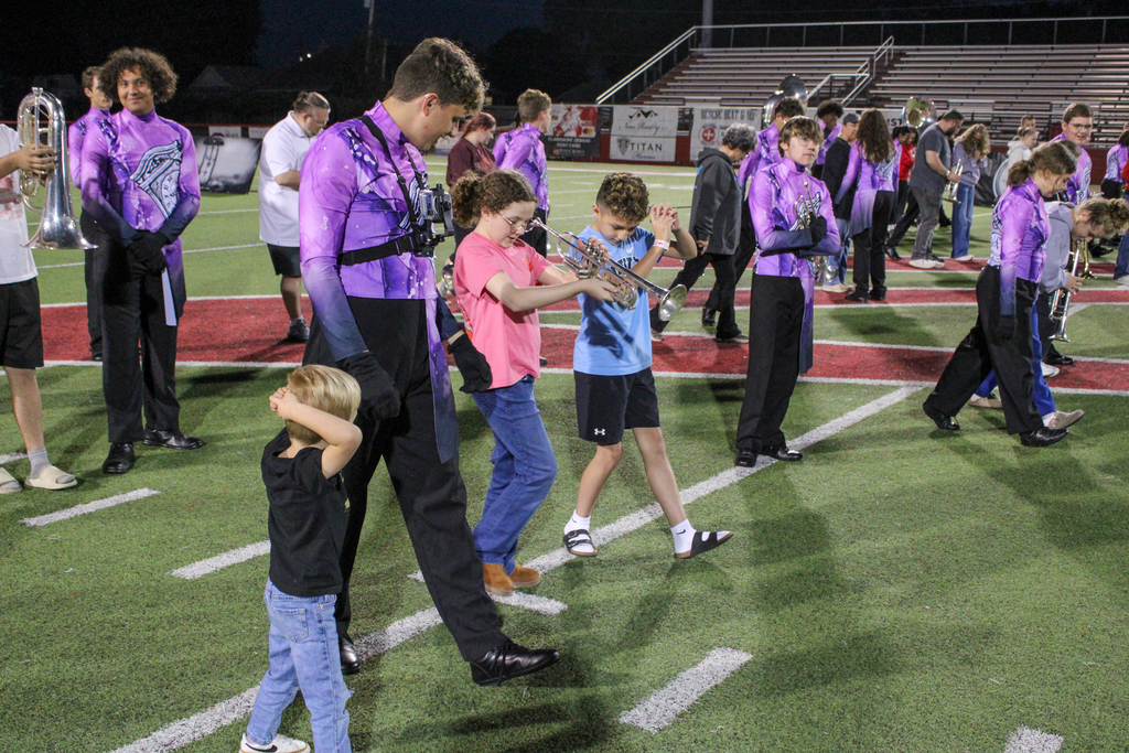 Band students help younger siblings learn to march and play instruments.
