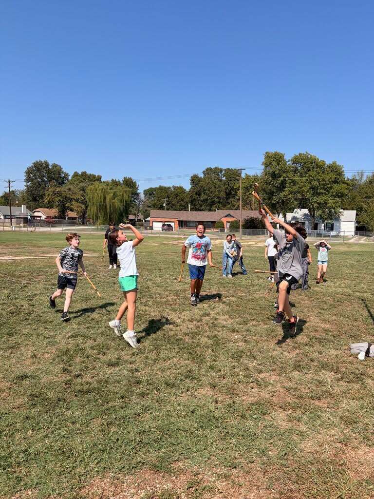 Students play stickball together on the school field.