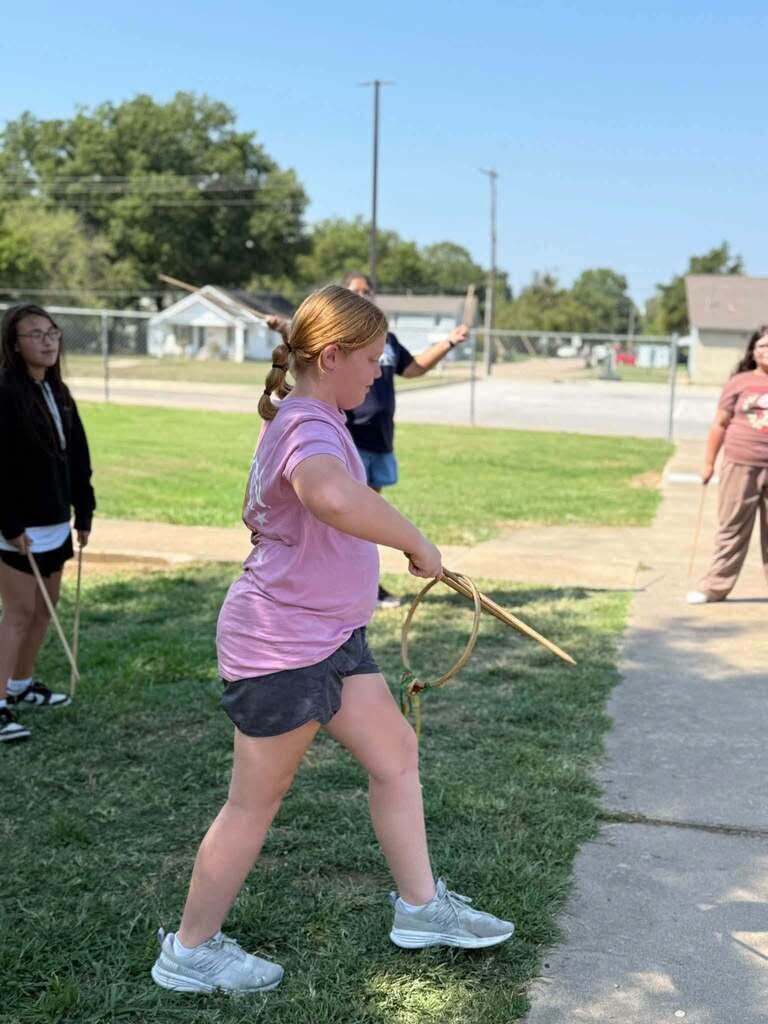 A student practices using a traditional stickball stick.