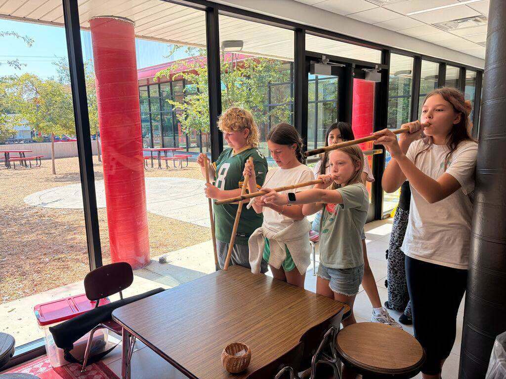 Students learn to use traditional blowguns during a hands-on demonstration.