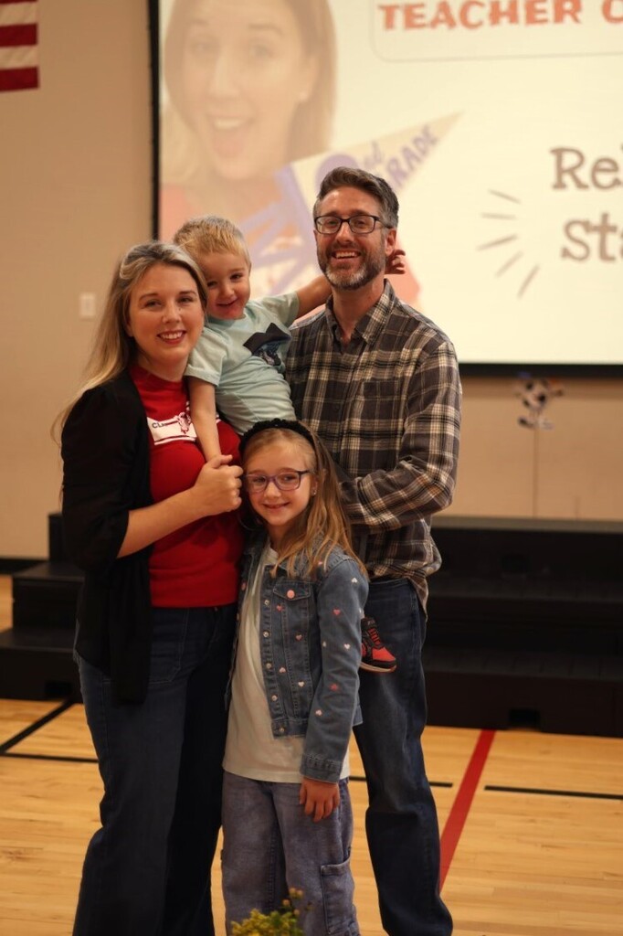 Mrs. Stanart and spouse and kids smiling in gym
