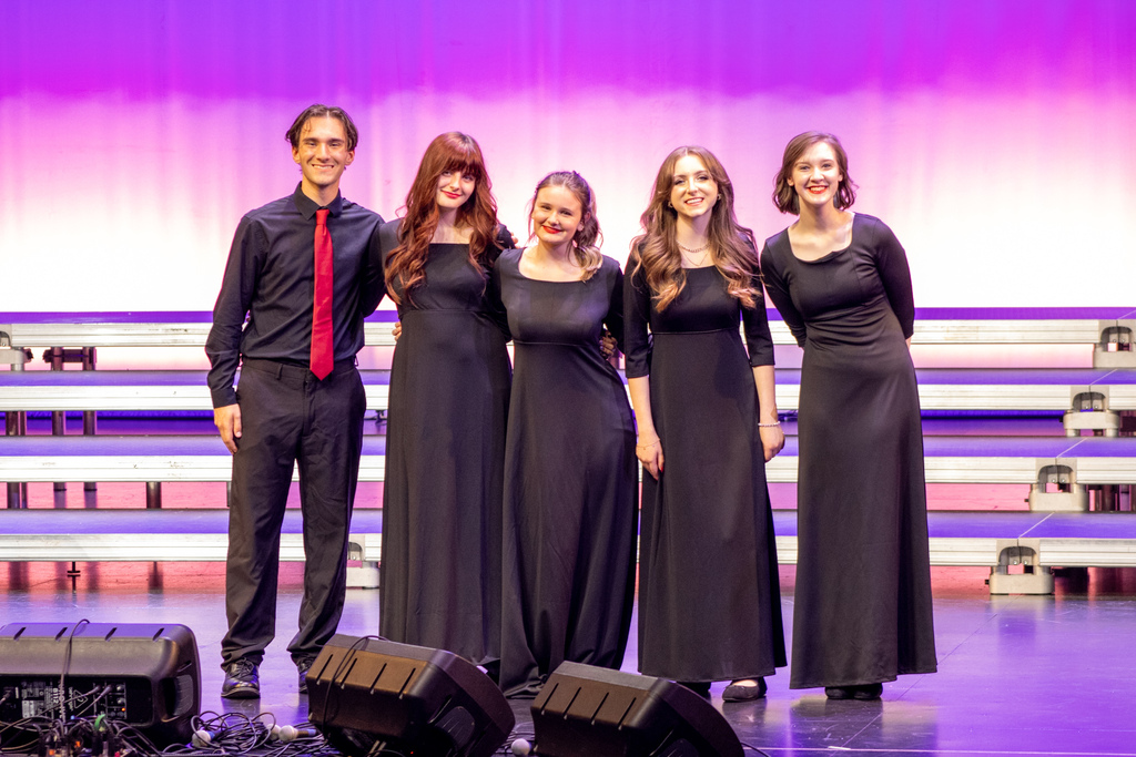 Five Claremore High School choir students posing together on stage after a performance.