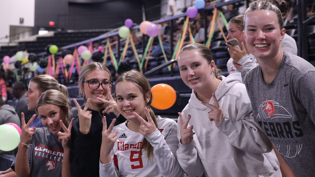 Claremore volleyball players smile and pose together in the stands.