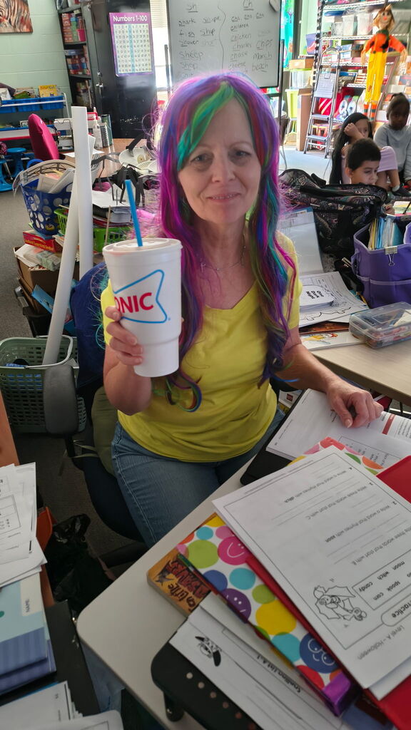 teacher holding a sonic drink, smiling