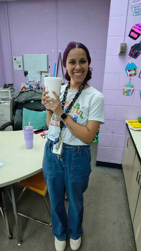 teacher holding a sonic drink, smiling