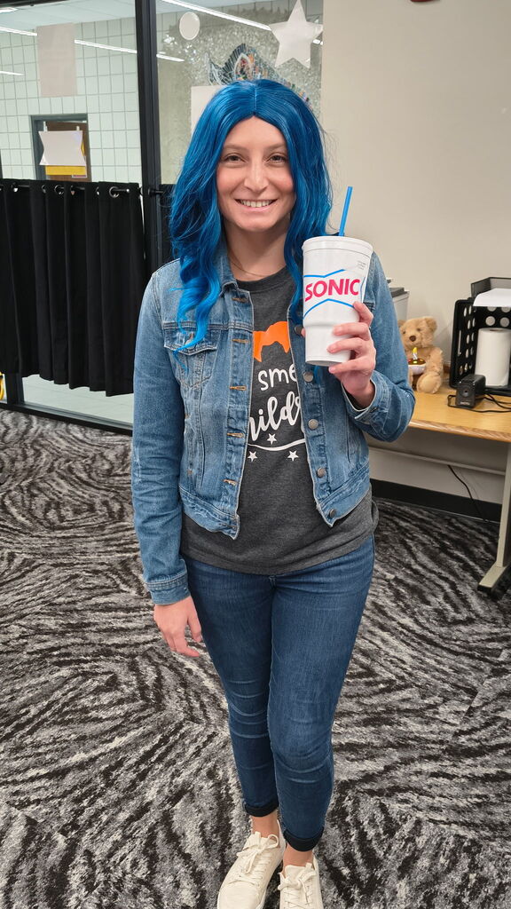 teacher holding a sonic drink, smiling