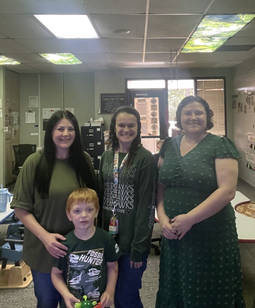 student and staff wearing green and smiling