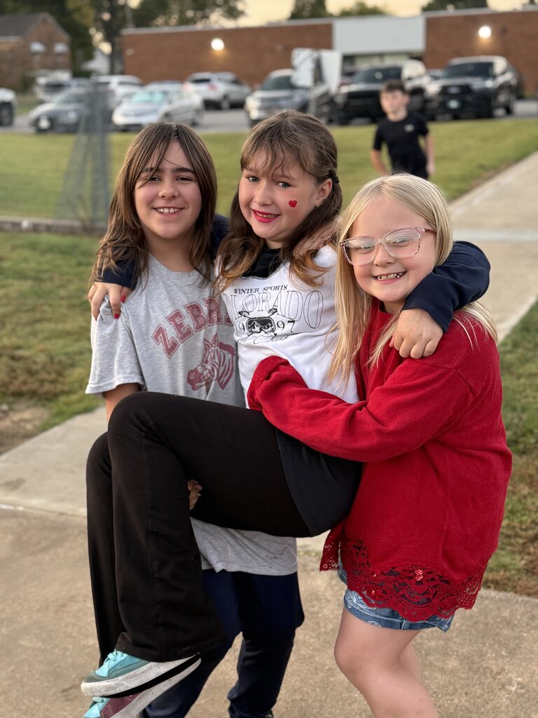 one student wearing red holding another student smiling
