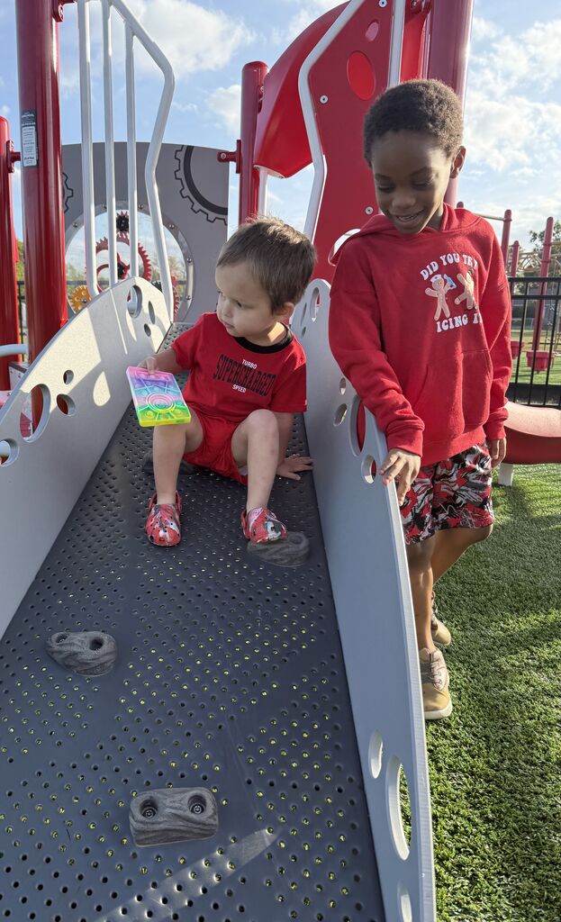 two students wearing red on the playground equipment 