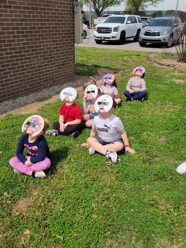 students in mask/glasses watching eclipse