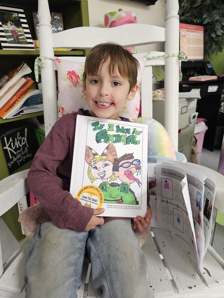 student shows off cover of book published for second grade